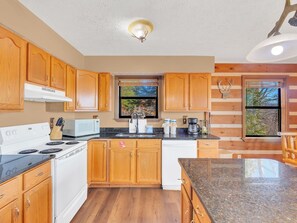 A kitchen with wooden cabinets, a stove, a microwave, and a sink. - Breathtaking Views | Close To Dollywood | Hot Tub | Pool Table | WiFi (Sevierville)