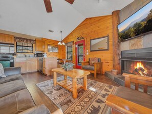 Un intérieur de chalet chaleureux comprenant une cuisine, un coin repas et une cheminée.