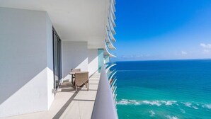 Un balcon avec vue sur l’océan, une table et deux chaises.