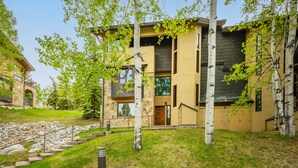 A modern two-story house with a stone facade, a wooden door, and a stone staircase leading to the entrance. - Residence #31 3 Bedroom Home (Snowmass Village)