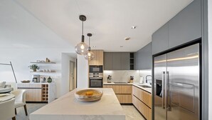 Une cuisine moderne dotée d’un îlot central, d’appareils électroménagers en acier inoxydable et d’un design minimaliste.