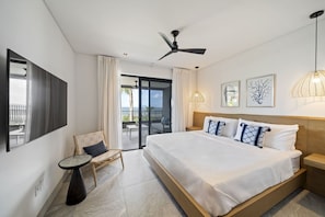 Une chambre d’hôtel avec un lit, une chaise, une table, un ventilateur de plafond et une vue sur l’extérieur.