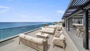 Une terrasse sur le toit avec des sièges extérieurs, une piscine et une vue sur l’océan.