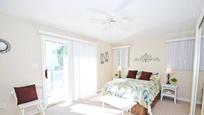A bedroom with a bed, a chair, a small table, a ceiling fan, and a window with blinds. - Coral Ridge 1 2 Bedroom Condo (Ocean City)