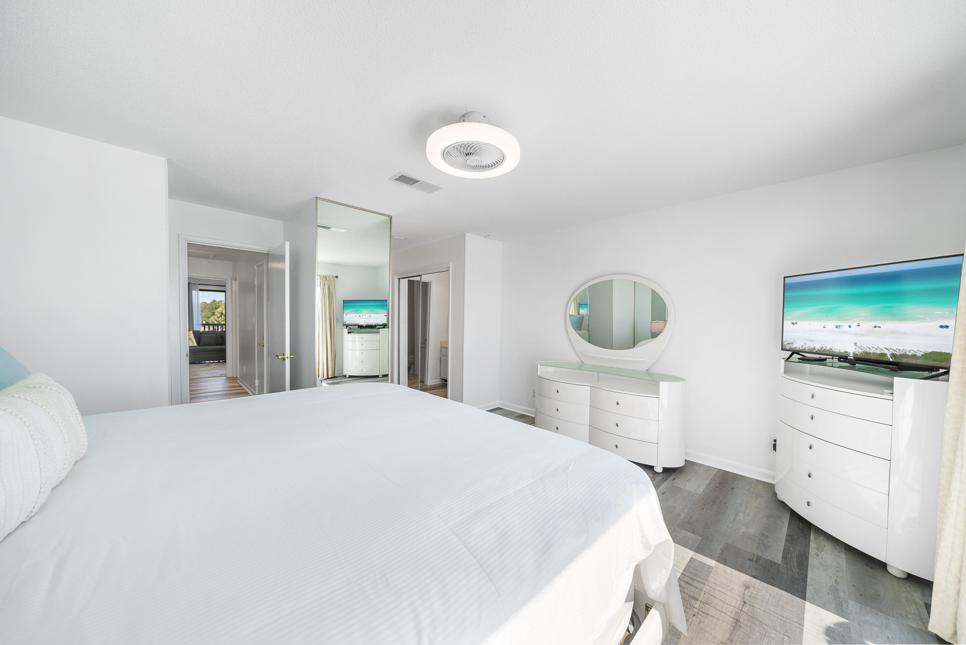 Une chambre moderne avec un grand lit, une télévision, une commode et un miroir.