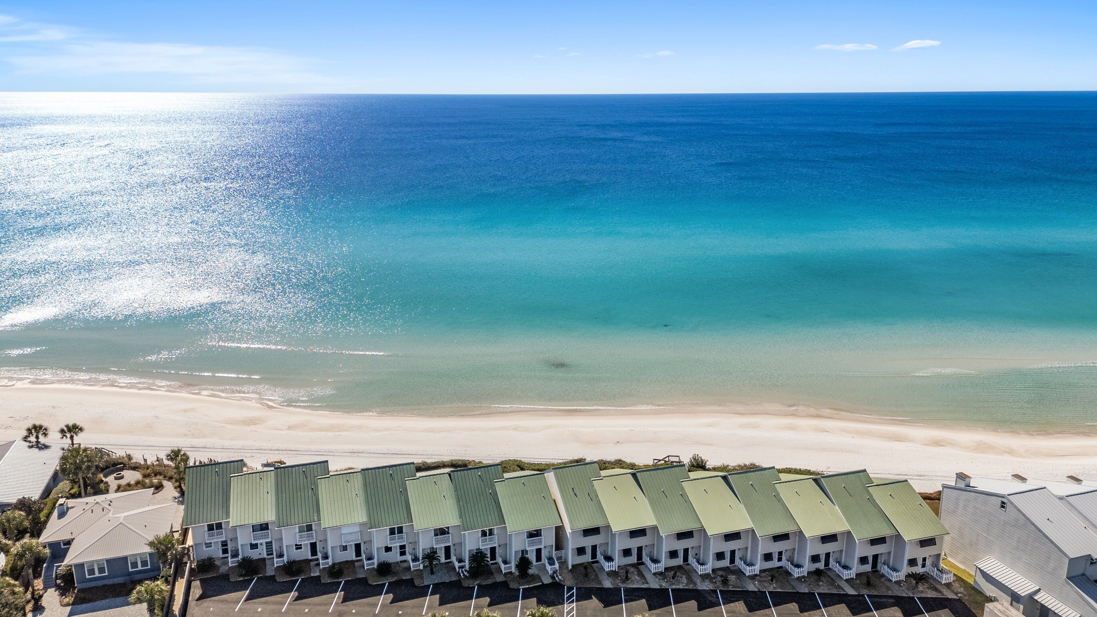 Ein Strandhotel mit mehreren Gebäuden, einem Parkplatz und Blick aufs Meer.