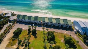 A beachfront hotel with multiple-story buildings, a parking lot, and a beach view.