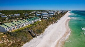 A coastal resort with beachside cottages, a sandy beach, and a clear view of the ocean.