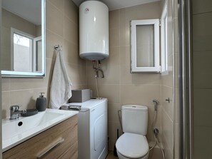 Ein modernes Badezimmer mit einem weißen Waschbecken, einer Toilette, einer Dusche und einer integrierten Heizung.