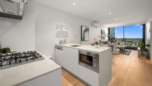 A modern kitchen with a central island, a built-in oven, and a gas stove. - Sky Glow-Southbank Designer Glamour with Bay views (Southbank)