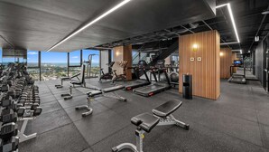 A modern gym with various exercise equipment, a bench press, and a treadmill. - Sky Glow-Southbank Designer Glamour with Bay views (Southbank)