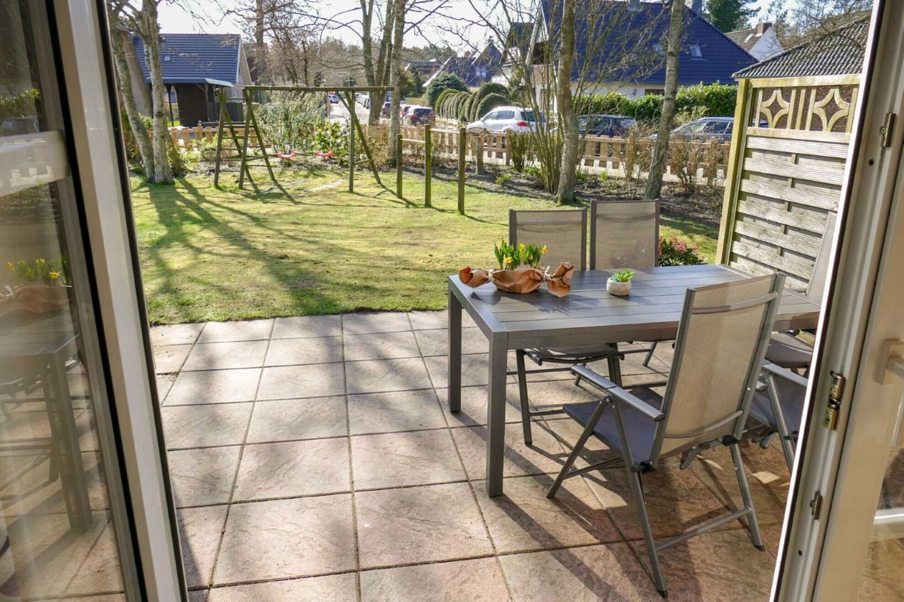 Eine Terrasse mit Tisch und Stühlen, ein kleiner Gartenbereich und Blick auf die Nachbarschaft.