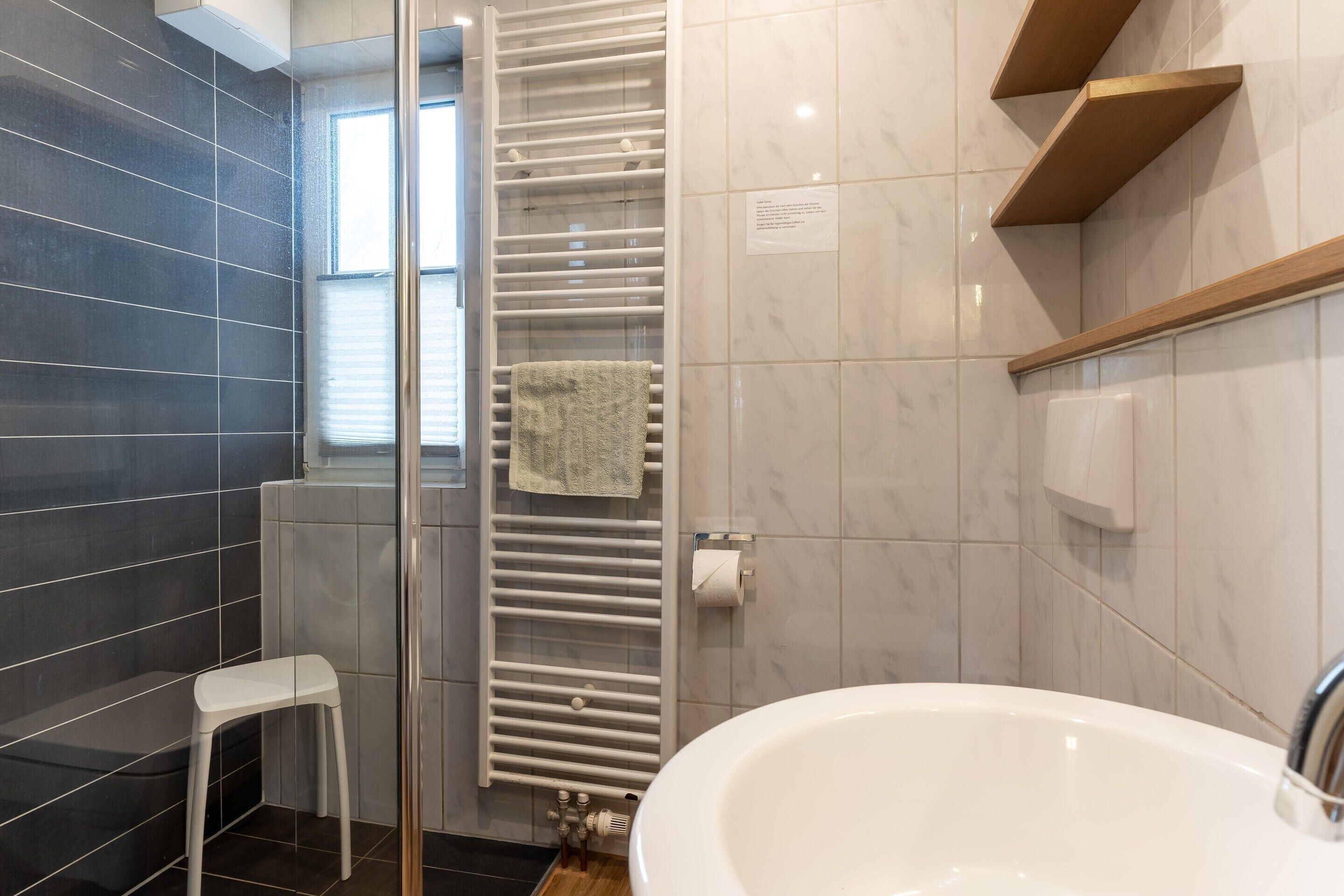 Un baño moderno con una bañera blanca, un perchero y un radiador.