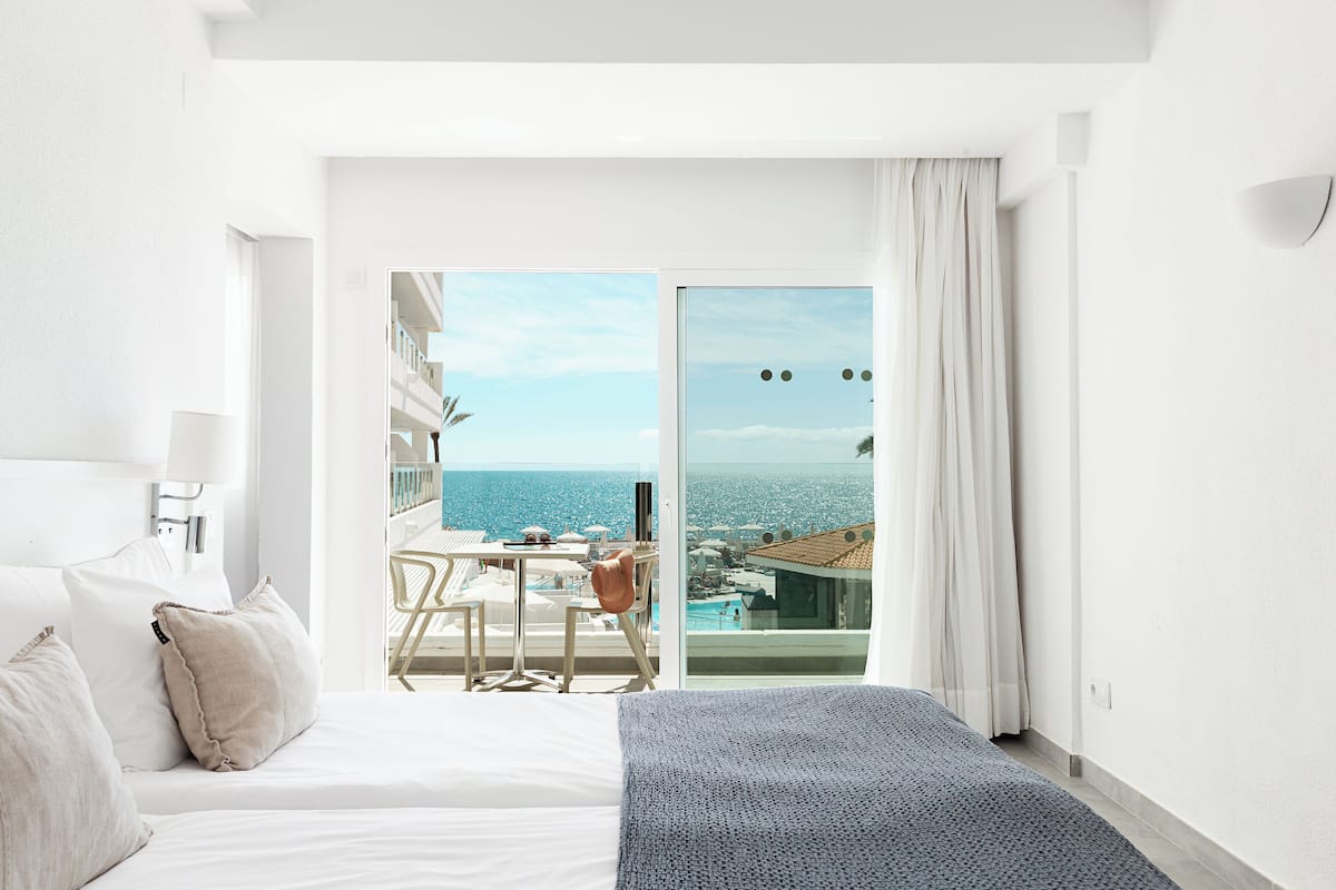 Une chambre d’hôtel avec un lit, un bureau et une vue sur la mer.