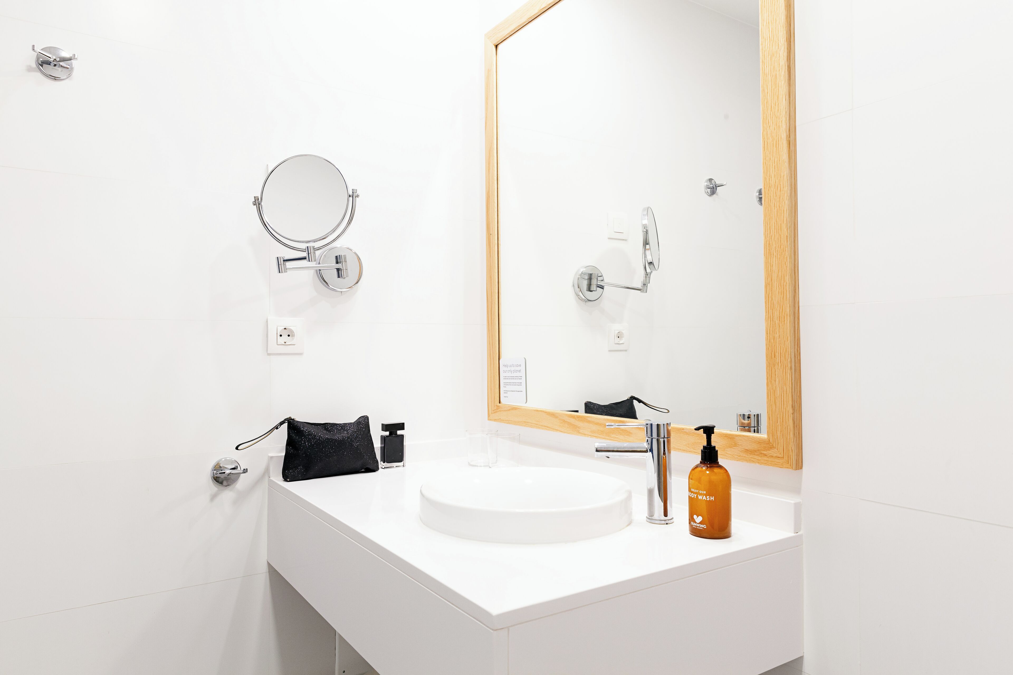 A modern bathroom with a white sink, a round mirror, and a large rectangular mirror.