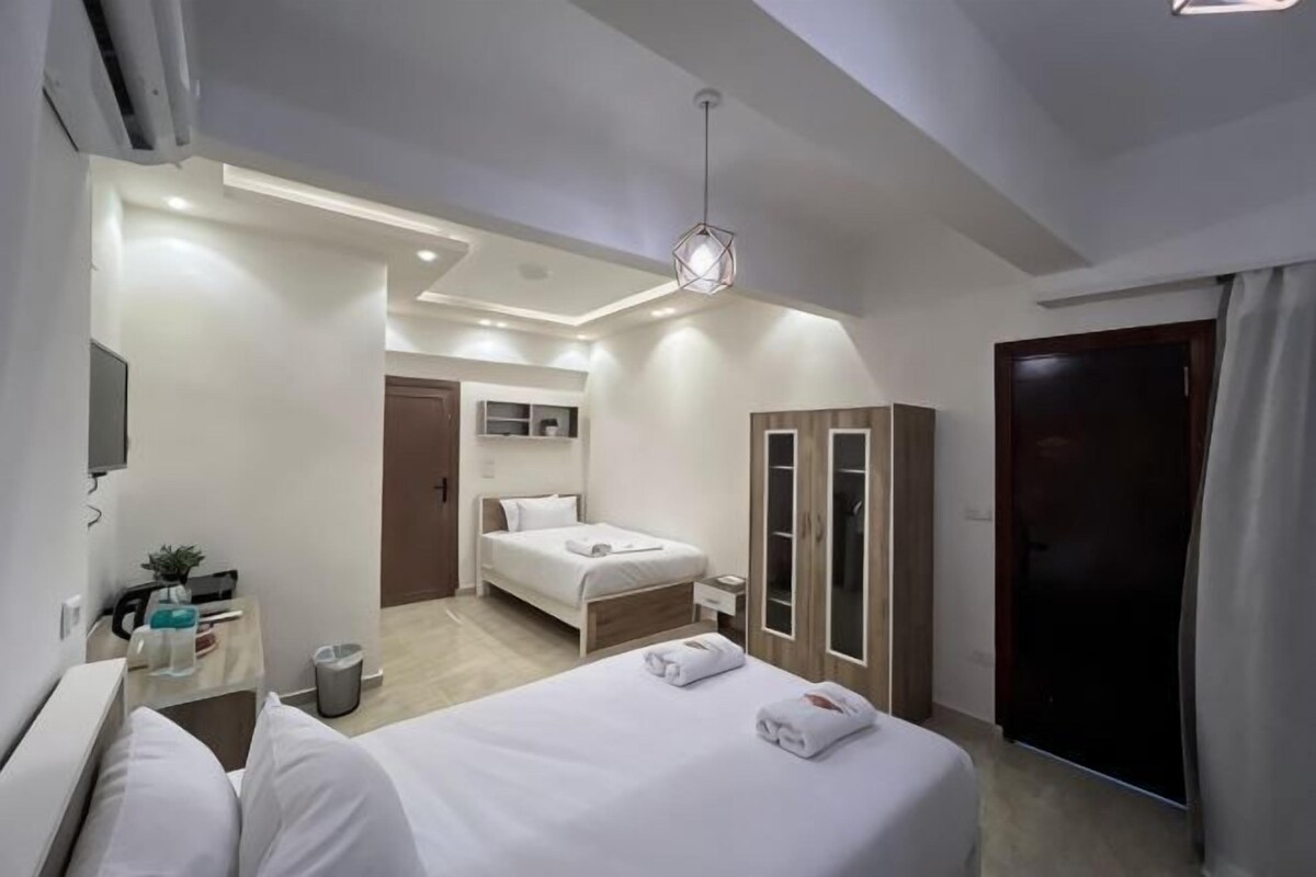 A modern hotel room with a bed, bedside table, wardrobe, and a television.