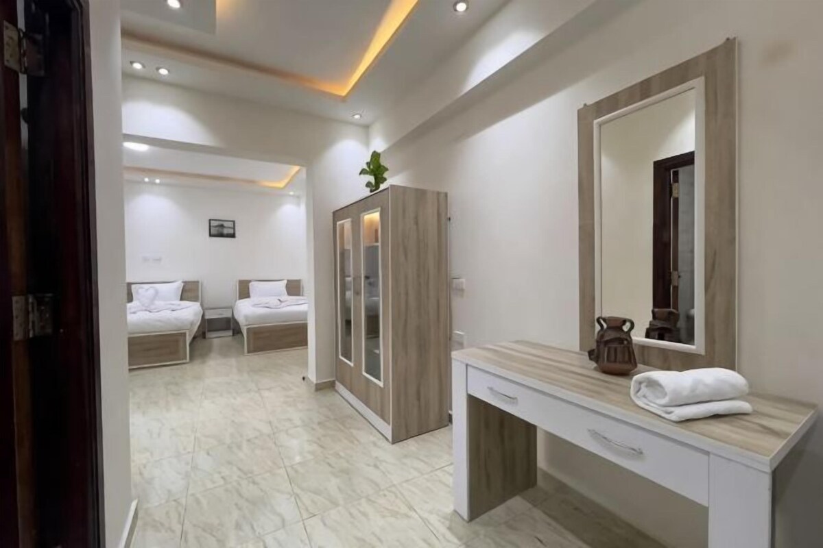 A hotel room with a bed, a wardrobe, a vanity with a mirror, and a desk.