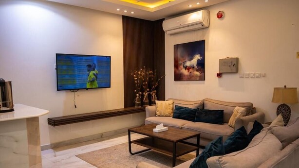 Ein modernes Wohnzimmer mit einer Couch, einem Couchtisch und einem an der Wand befestigten Flachbildfernseher.