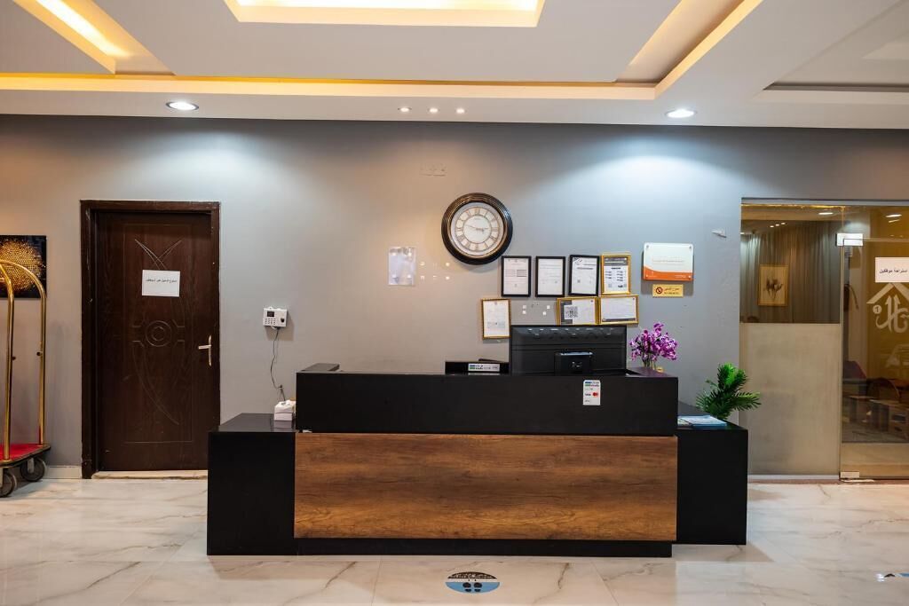 A reception desk with a clock, framed certificates, and a small plant.