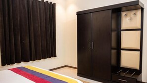 Ein Schlafzimmer mit einem Bett, einem dunklen Wandschrank und Vorhängen.