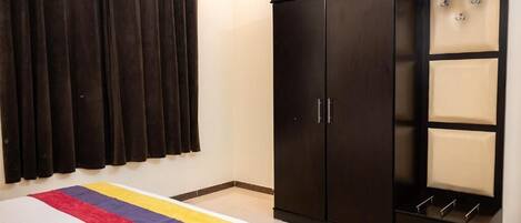 Quarto com cama, guarda-roupa escuro e cortinas.