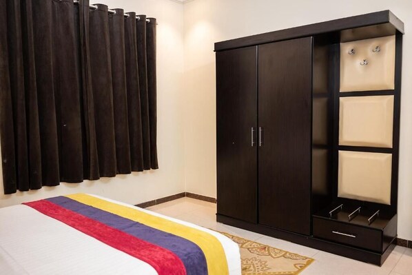 A bedroom with a bed, dark wardrobe, and curtains.
