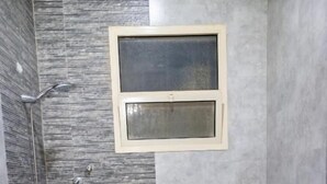Ein Badezimmer mit Dusche, Toilette und einem kleinen Fenster.