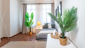 A modern bedroom with a bed, bedside table, lamp, and potted plants. - Spacious Apartment in Strausberg - Sleeps 6 (Strausberg)