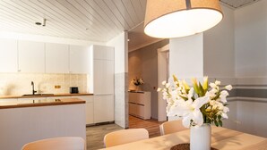 A modern kitchen with white cabinets, a wooden countertop, and a dining area with a table and chairs. - Spacious Apartment in Strausberg - Sleeps 6 (Strausberg)