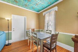 Une salle à manger avec une table et des chaises, un lampadaire et une fenêtre avec des rideaux.