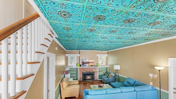 A living room with a fireplace, blue sofa, and a staircase with white railings.