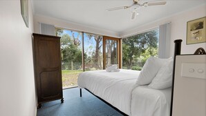 A bedroom with a bed, a wardrobe, and a ceiling fan. - The House - Waterfront Retreat: Secluded lodges perfect for nature lovers (Forge Creek)