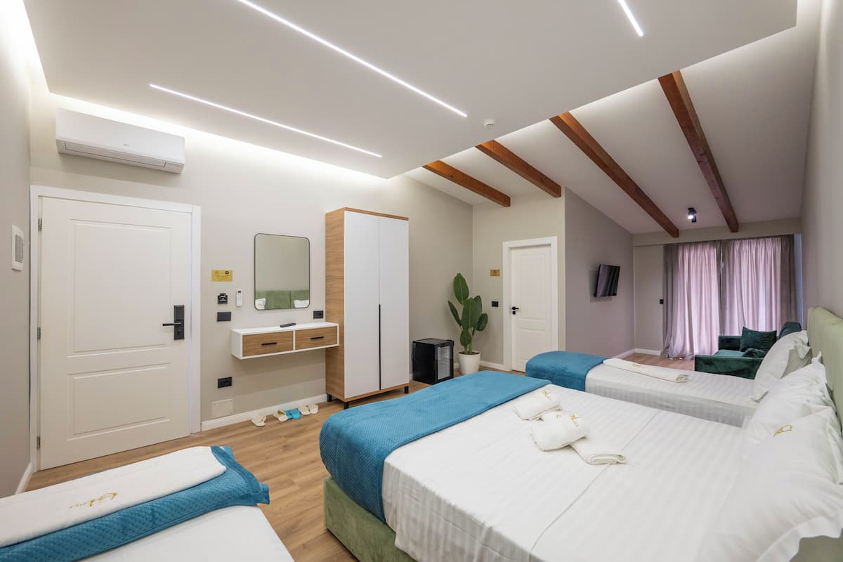 A hotel room with two beds, a desk, a mirror, and a TV.