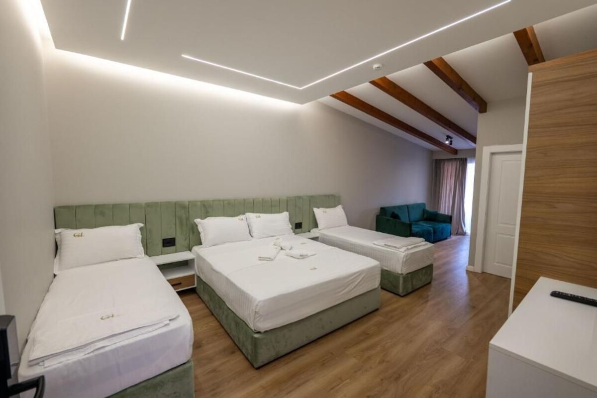 Une chambre d’hôtel moderne avec deux lits simples, un canapé et une télévision.