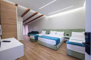 Ein modernes Hotelzimmer mit drei Betten, einem weißen Schreibtisch und einem Fernseher.
