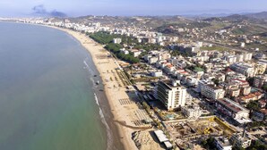 An aerial view of a coastal city with a beach, buildings, and a construction site. - Golemi Lux Hotel (Golem)