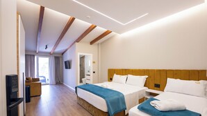 A hotel room with two beds, wooden beams on the ceiling, a television, a desk, and a bathroom visible through an open door. - Golemi Lux Hotel (Golem)