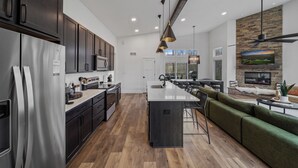 A modern kitchen with dark cabinets, stainless steel appliances, and a central island.