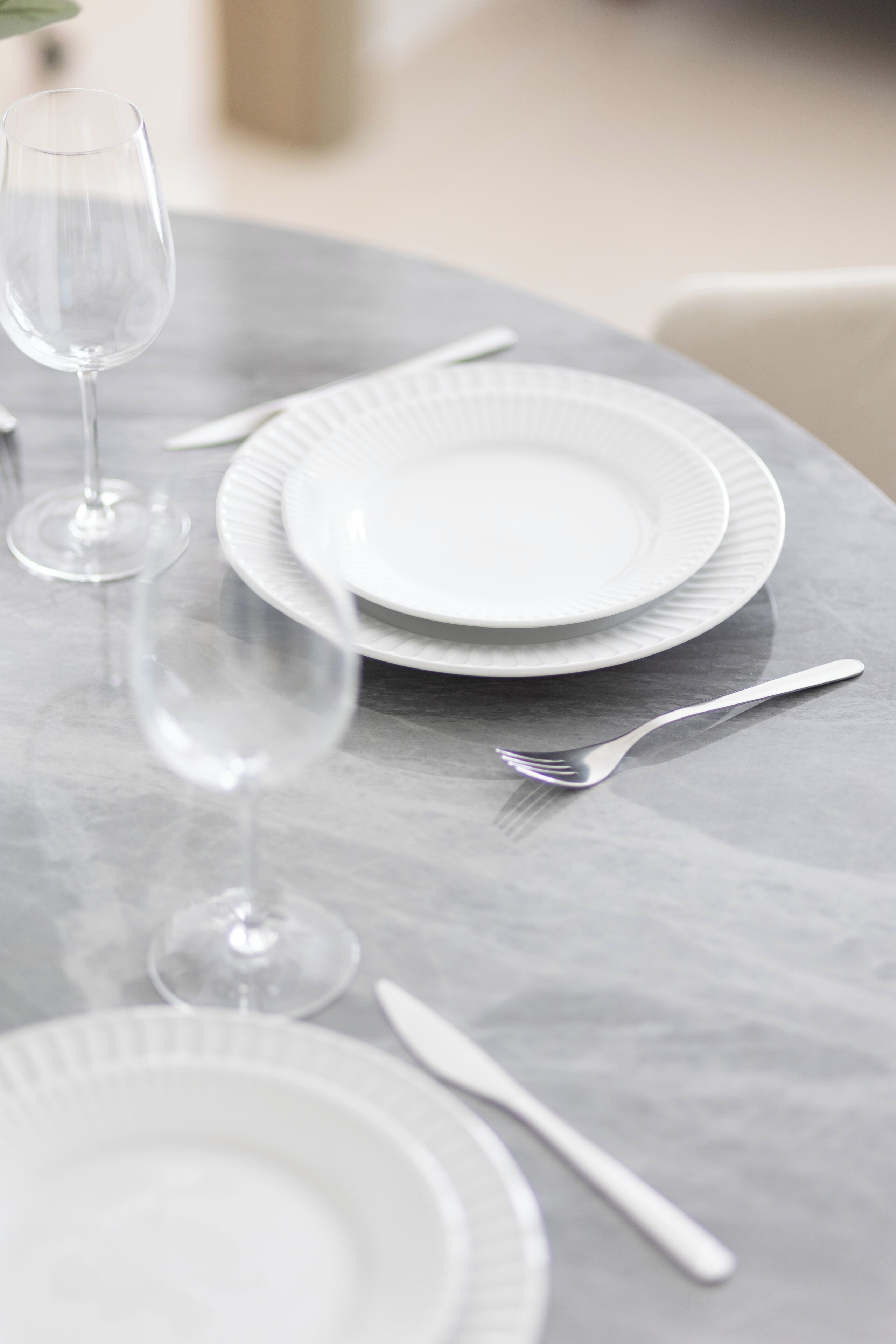 A table set with white plates, a fork, and a wine glass.