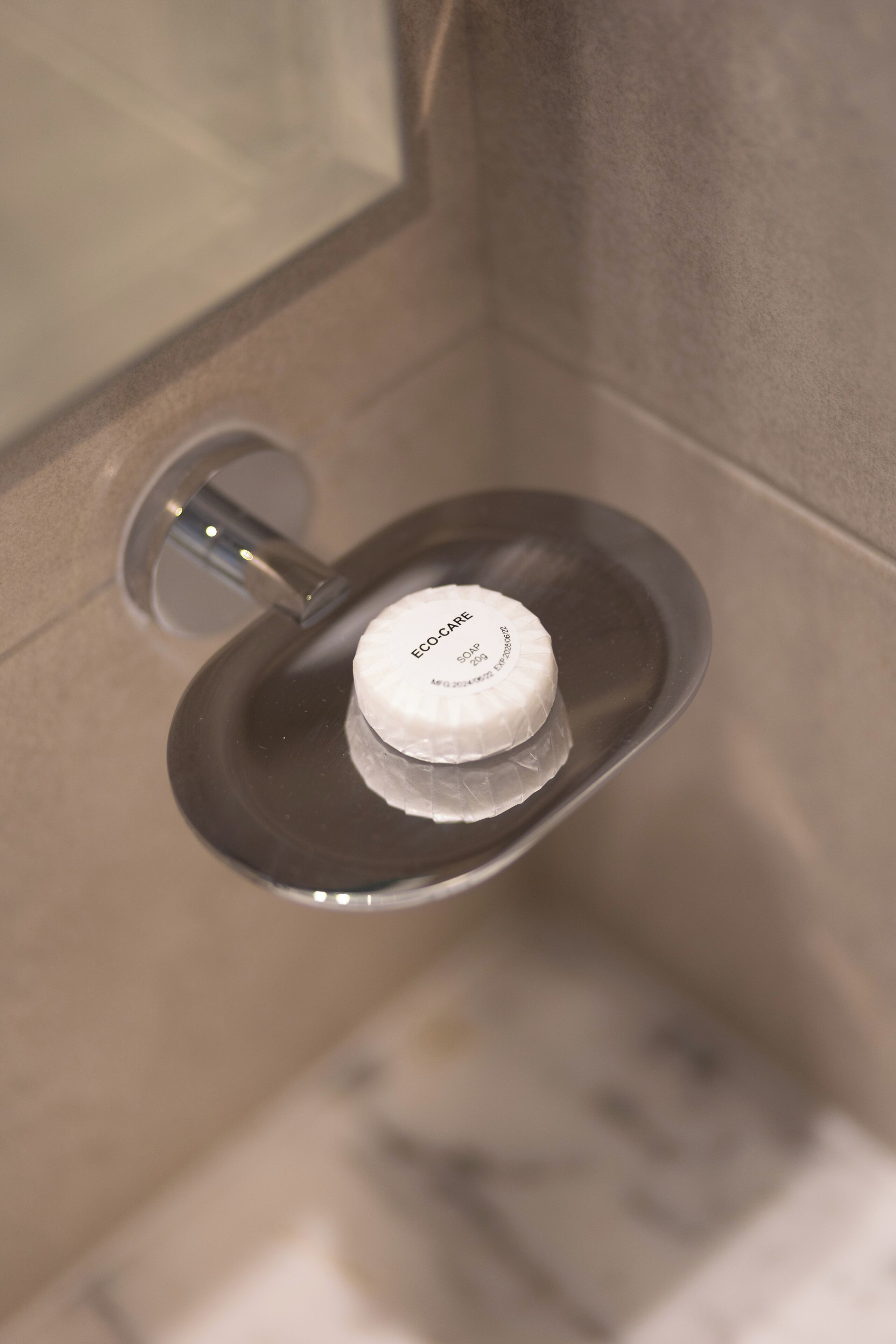 Un baño de diseño moderno, con un inodoro de plato plateado y tapa blanca etiquetada como "ECOCARE".