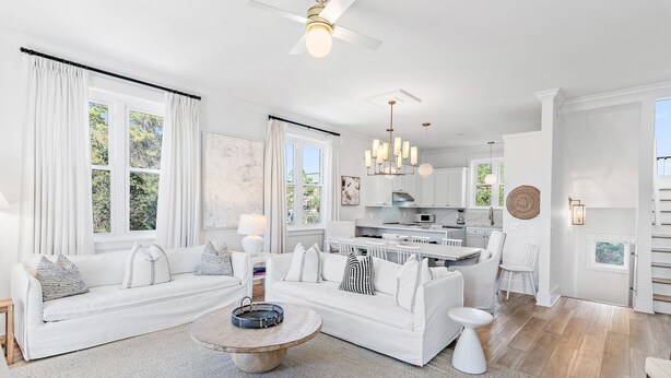 A spacious living room with a white sofa, a coffee table, and a kitchen area visible in the background. - Top Location on 30A Bordering Rosemary Beach with Private Pool and Beach (Inlet Beach)