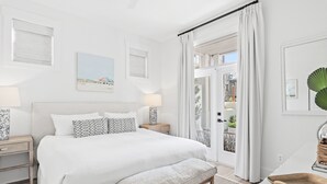 A bedroom with a large bed, bedside tables, a bench, and a view of the outdoors. - Top Location on 30A Bordering Rosemary Beach with Private Pool and Beach (Inlet Beach)