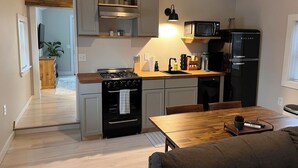 Una cocina moderna con estufa, microondas y refrigerador, armarios de madera y un comedor con mesa y sillas.