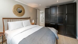 Une chambre à coucher comprenant un lit, une table de chevet, une lampe, une armoire et un miroir rond accroché au mur.