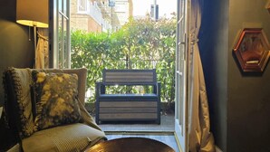 Une pièce comprenant un canapé, un banc et donnant sur un jardin et des bâtiments situés à l’extérieur.