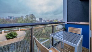 A balcony with a table and chairs, a potted plant, and a view of buildings and trees. - Lovely 3BD Flat, Parking, sleeps SIX close to O2 (London)