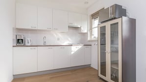 Une cuisine moderne avec des meubles blancs, un réfrigérateur en acier inoxydable et une machine à café.