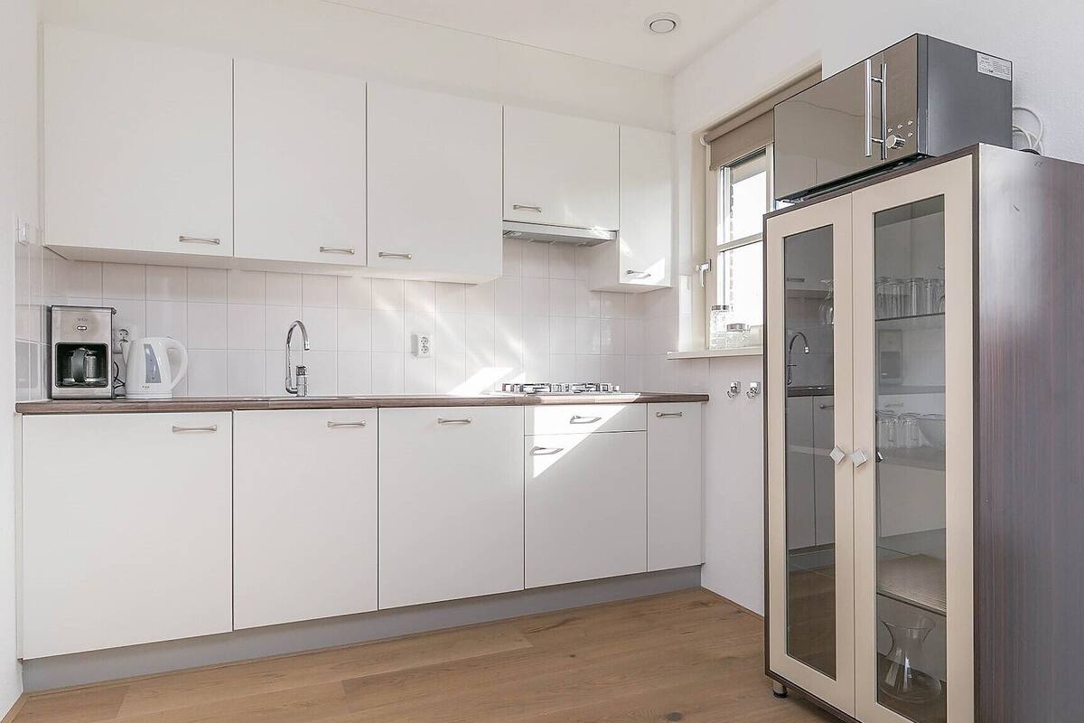 Een moderne keuken met witte kasten, een roestvrijstalen koelkast en een koffiezetapparaat.