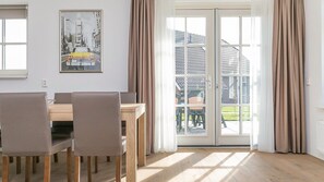 Un comedor con una mesa y sillas de madera, un cuadro en la pared y un toldo corredero que da a un patio exterior.