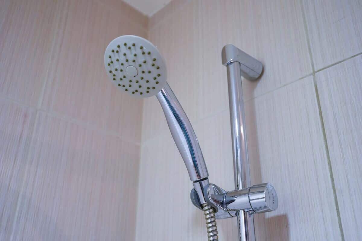 Un soffione doccia con un tubo flessibile collegato a un rubinetto a parete.